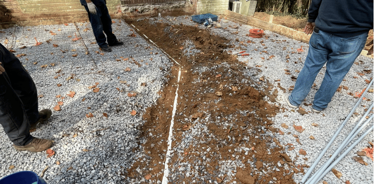 Workers excavating a trench in a gravel yard for sewer line repair in Germantown, MD